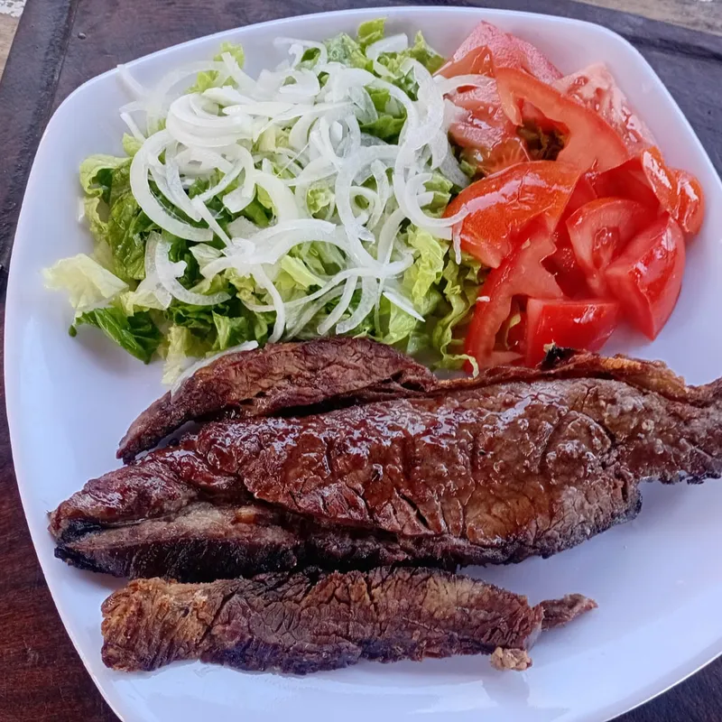Carne a la parrilla con ensalada de lechuga, tomate y cebolla